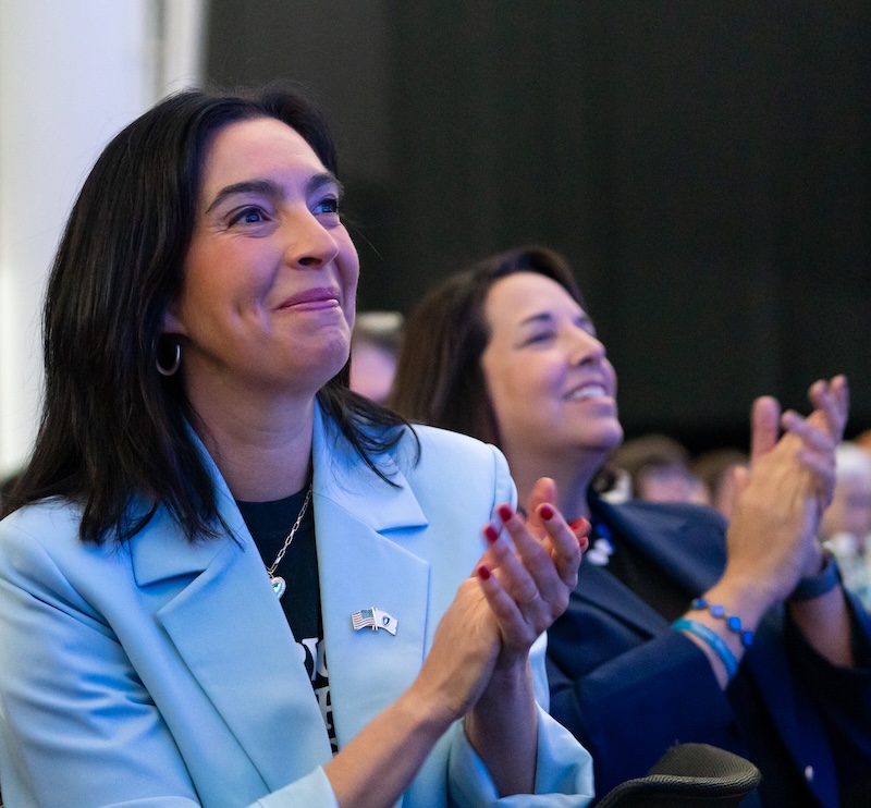Smiling women clapping at an event.