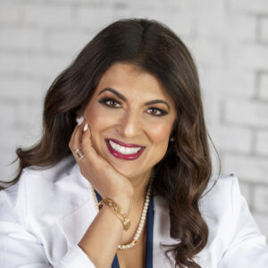 Smiling person with long hair and jewelry.