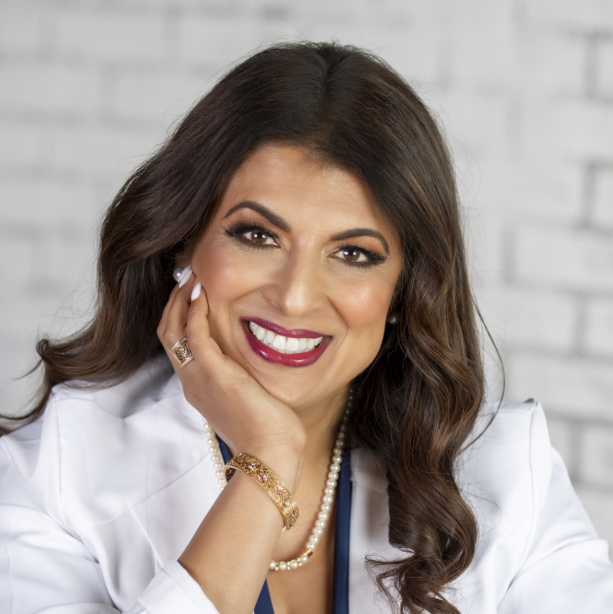 Smiling person with long hair and jewelry.