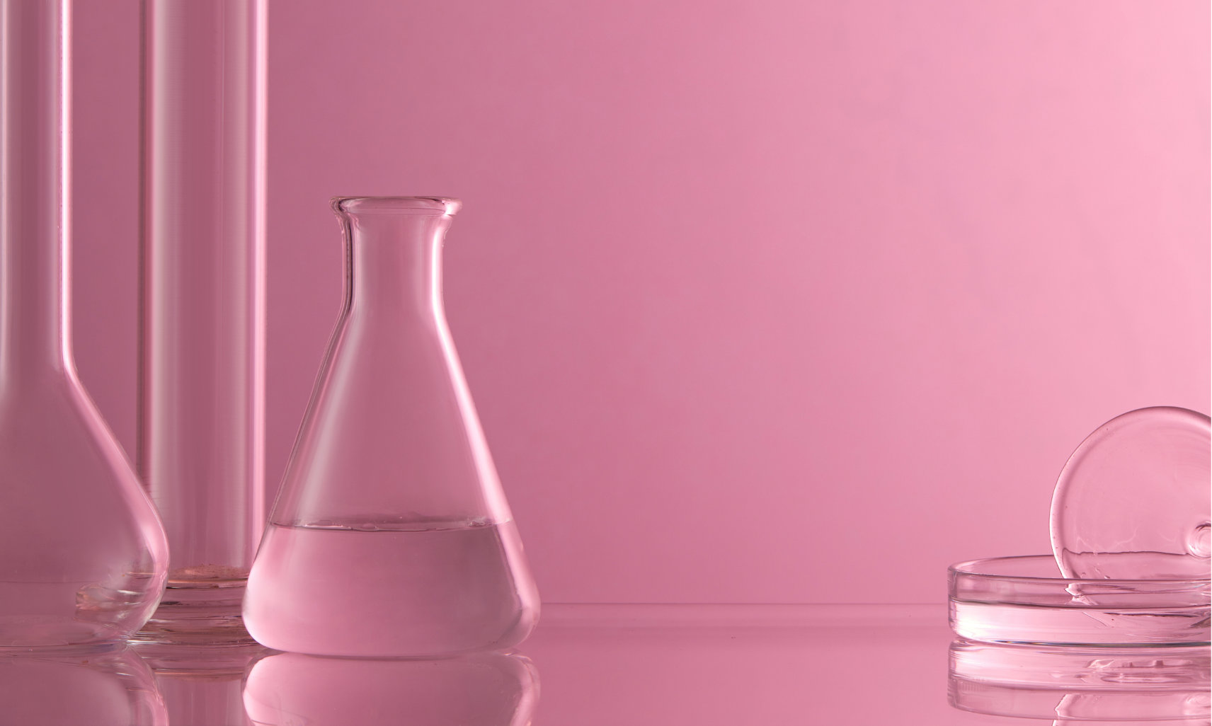 glass laboratory beakers on pink background