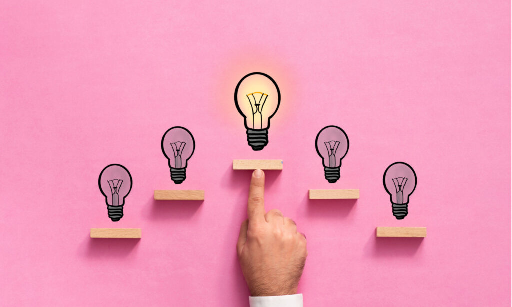 hand pointing to glowing light bulb illustration on pink background