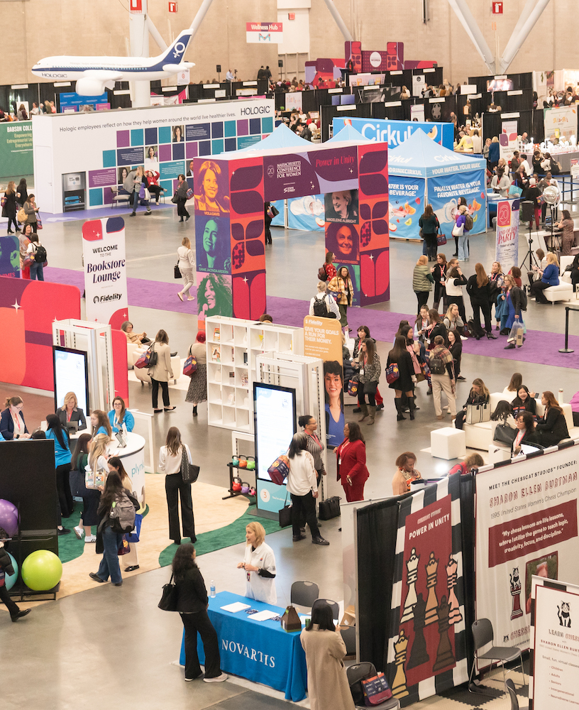 Busy conference hall with colorful booths and attendees.
