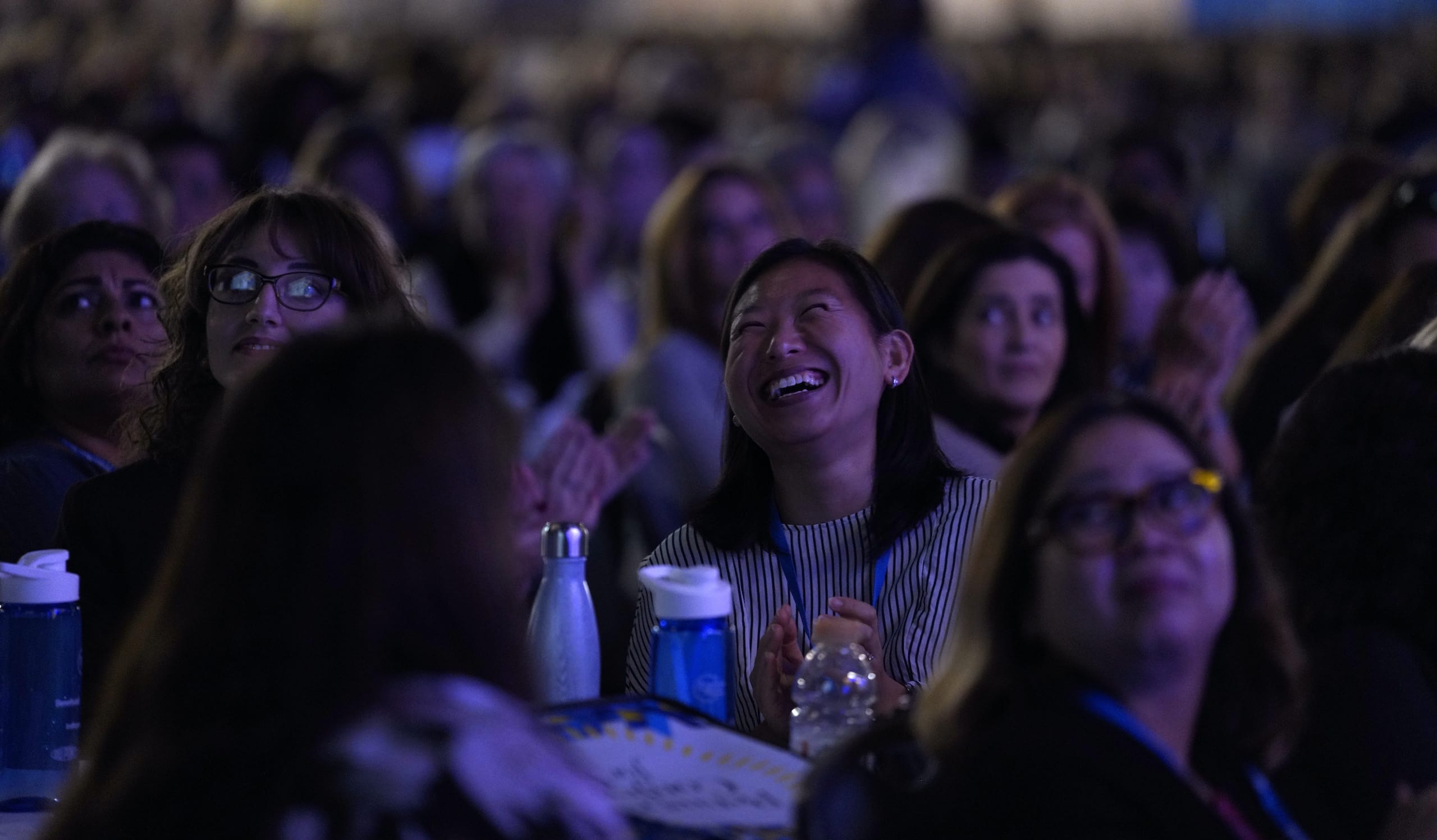 Audience clapping and smiling at event.