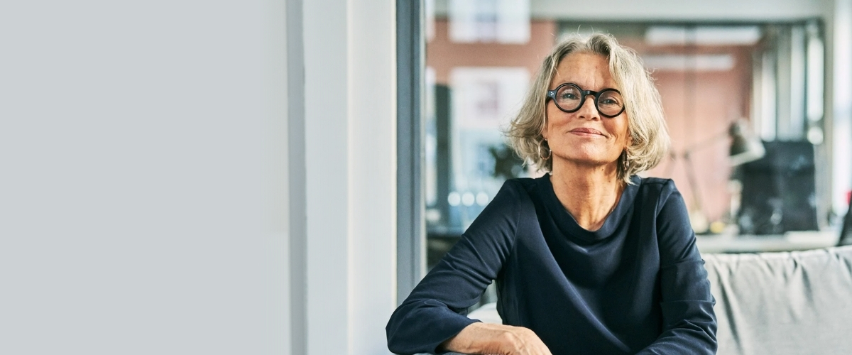 Smiling woman with glasses sitting indoors.