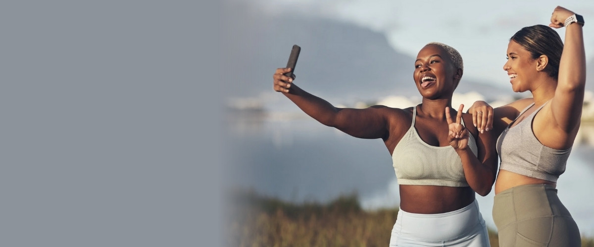 Two women taking selfie outdoors, smiling.