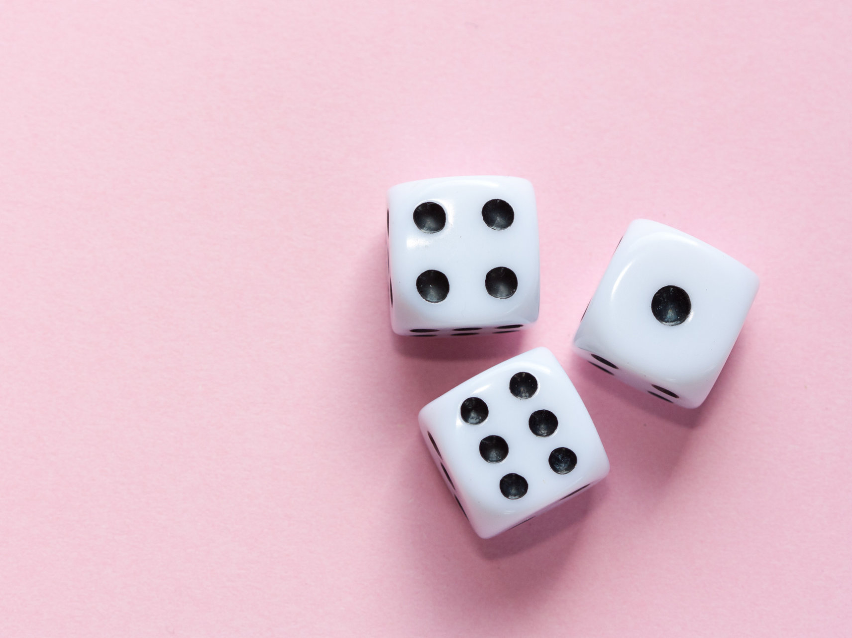 Three white dice on pink background