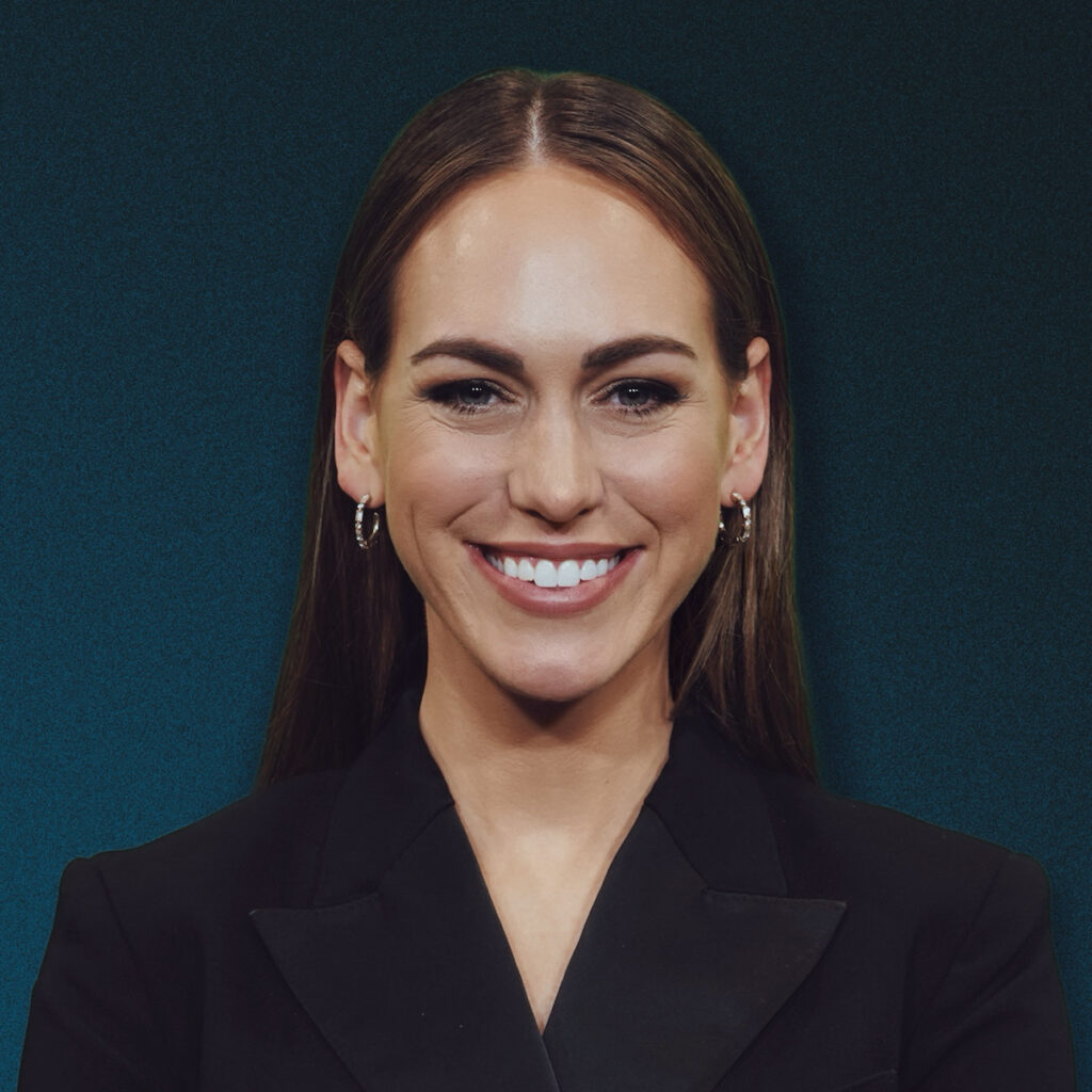 Smiling woman in black blazer against teal background