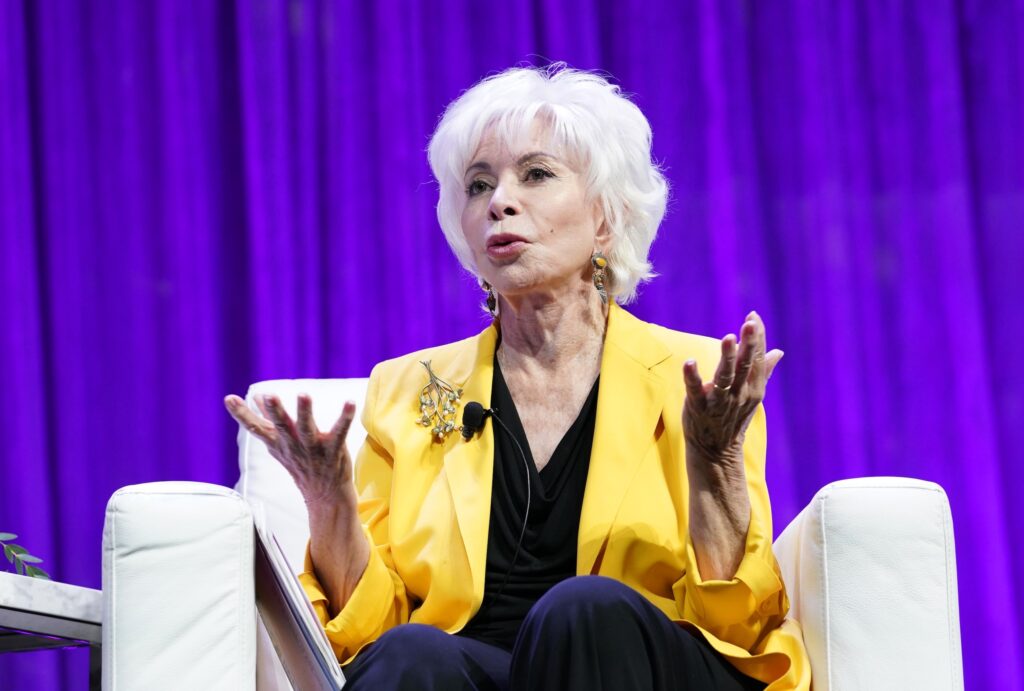 Isabel Allende speaking on stage in yellow jacket.