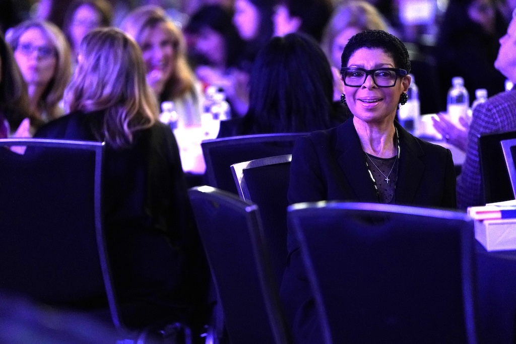 Woman sitting at an event with people.