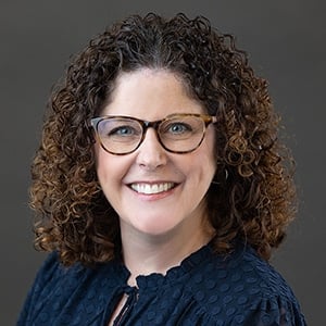 Smiling woman with curly hair and glasses portrait