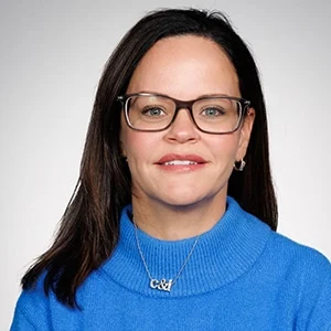 Woman wearing glasses and blue sweater smiling