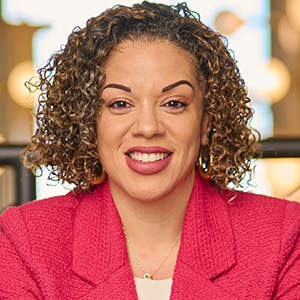 Smiling woman wearing a bright pink blazer indoors