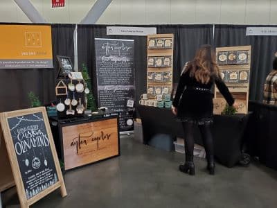 Woman browsing handcrafted ornaments at artisan market booth