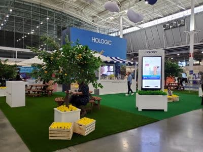 Hologic exhibition booth with greenery and seating area