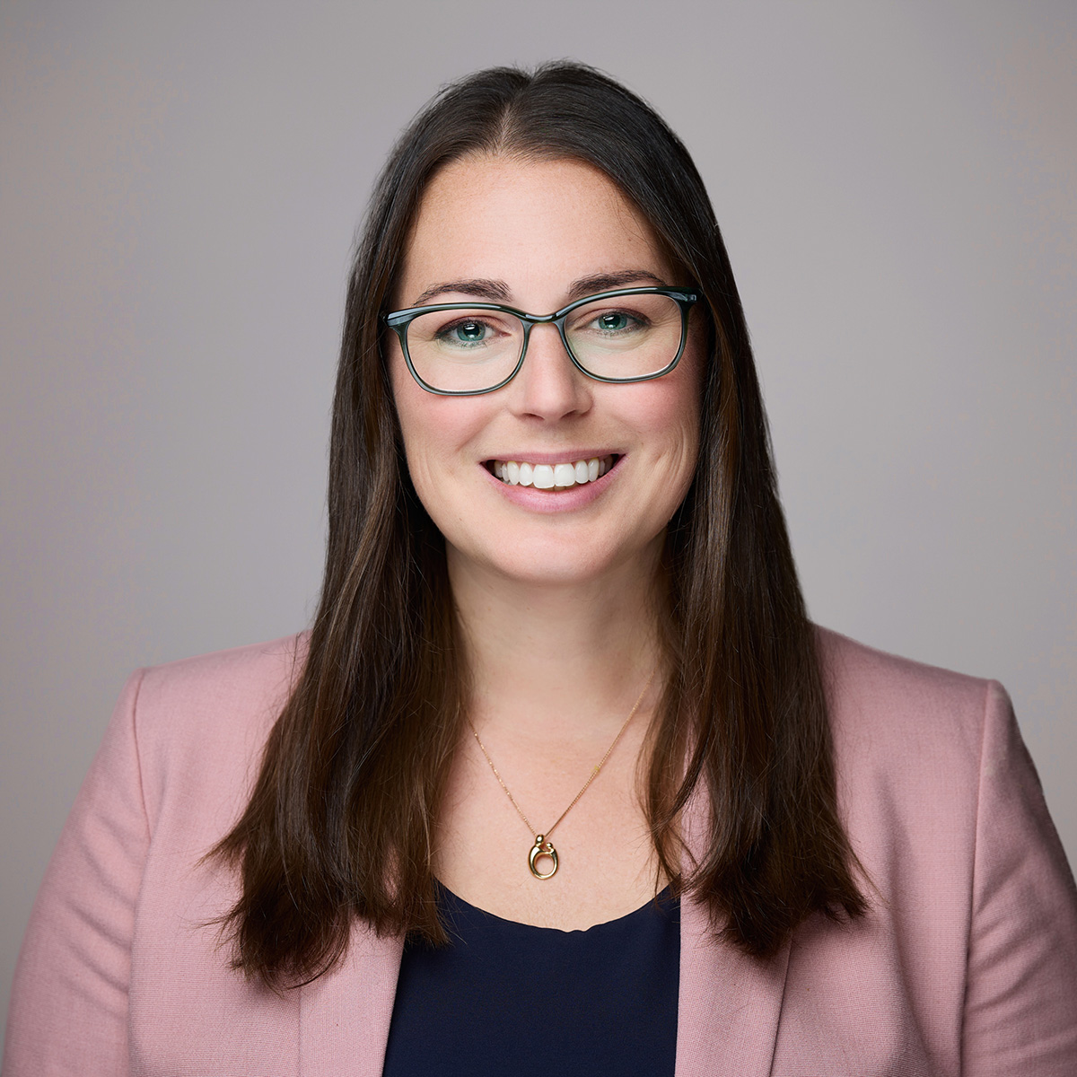 Smiling woman wearing glasses and pink blazer
