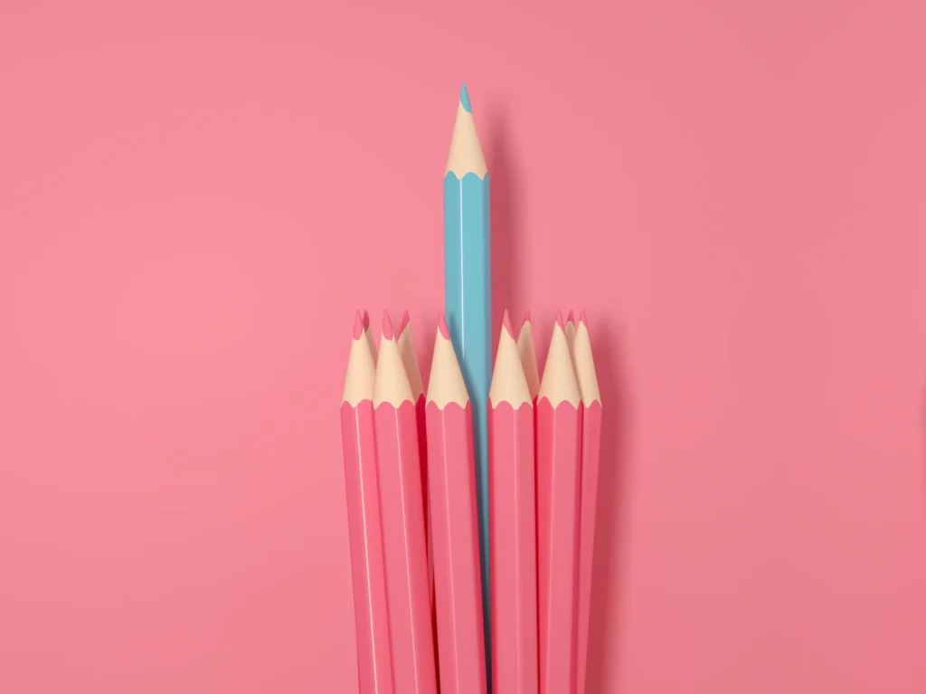 pink colored pencils on pink background with blue colored pencil in the middle