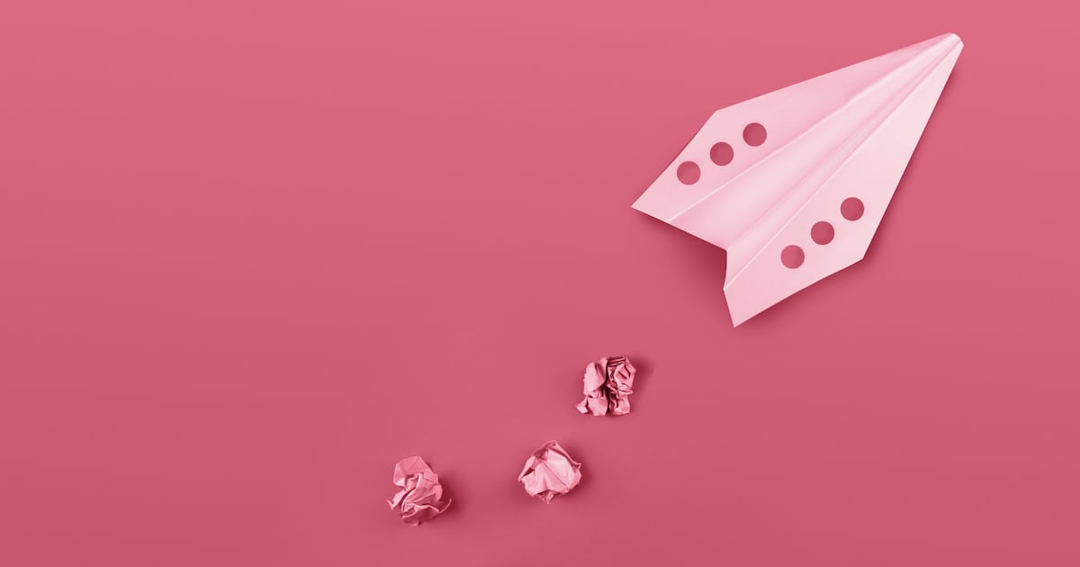 Flat lay of color paper plane colored in trendy color of the year 2023 Viva Magenta