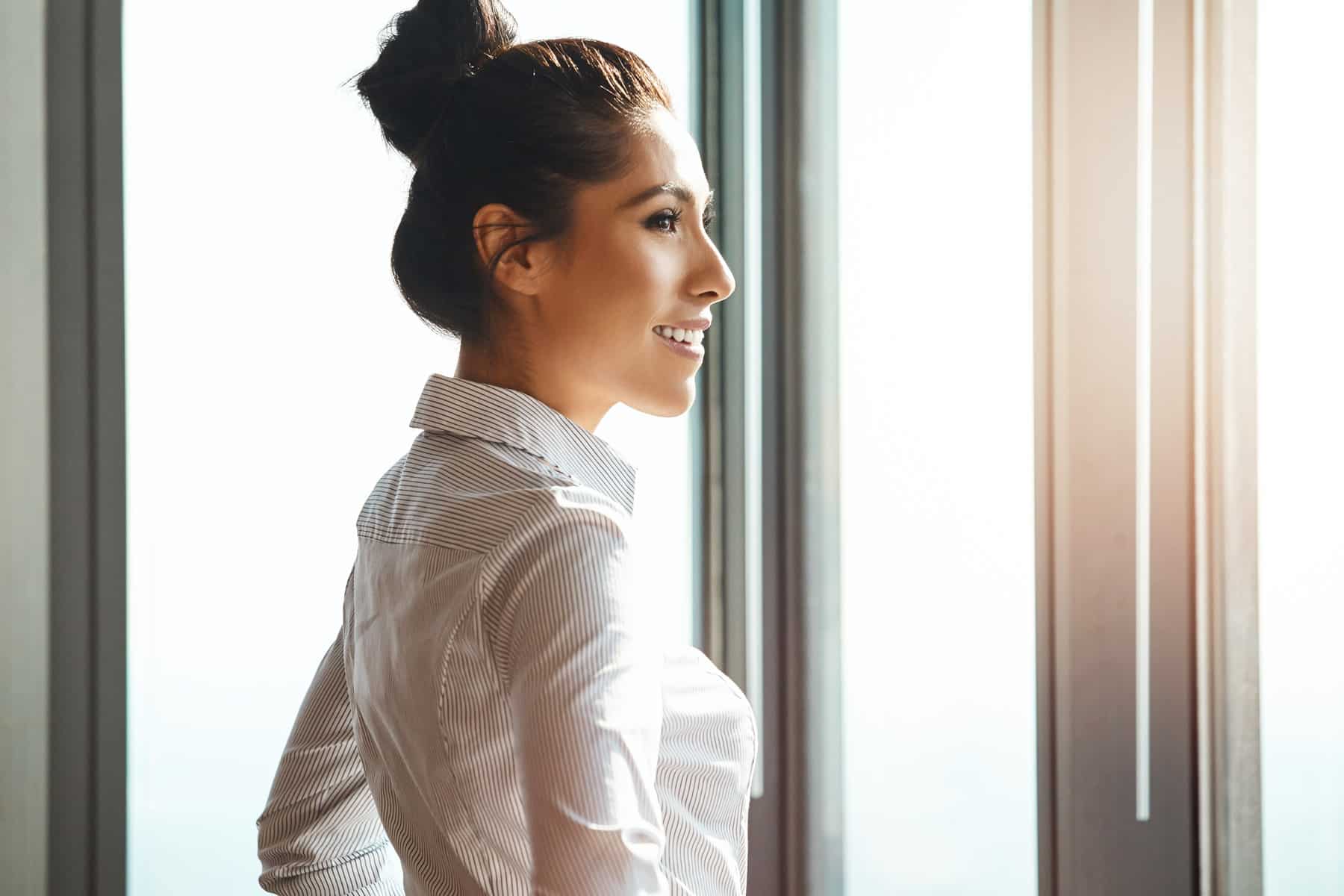young, smiling, sucessful businesswoman standing with her hands on her hips in the office