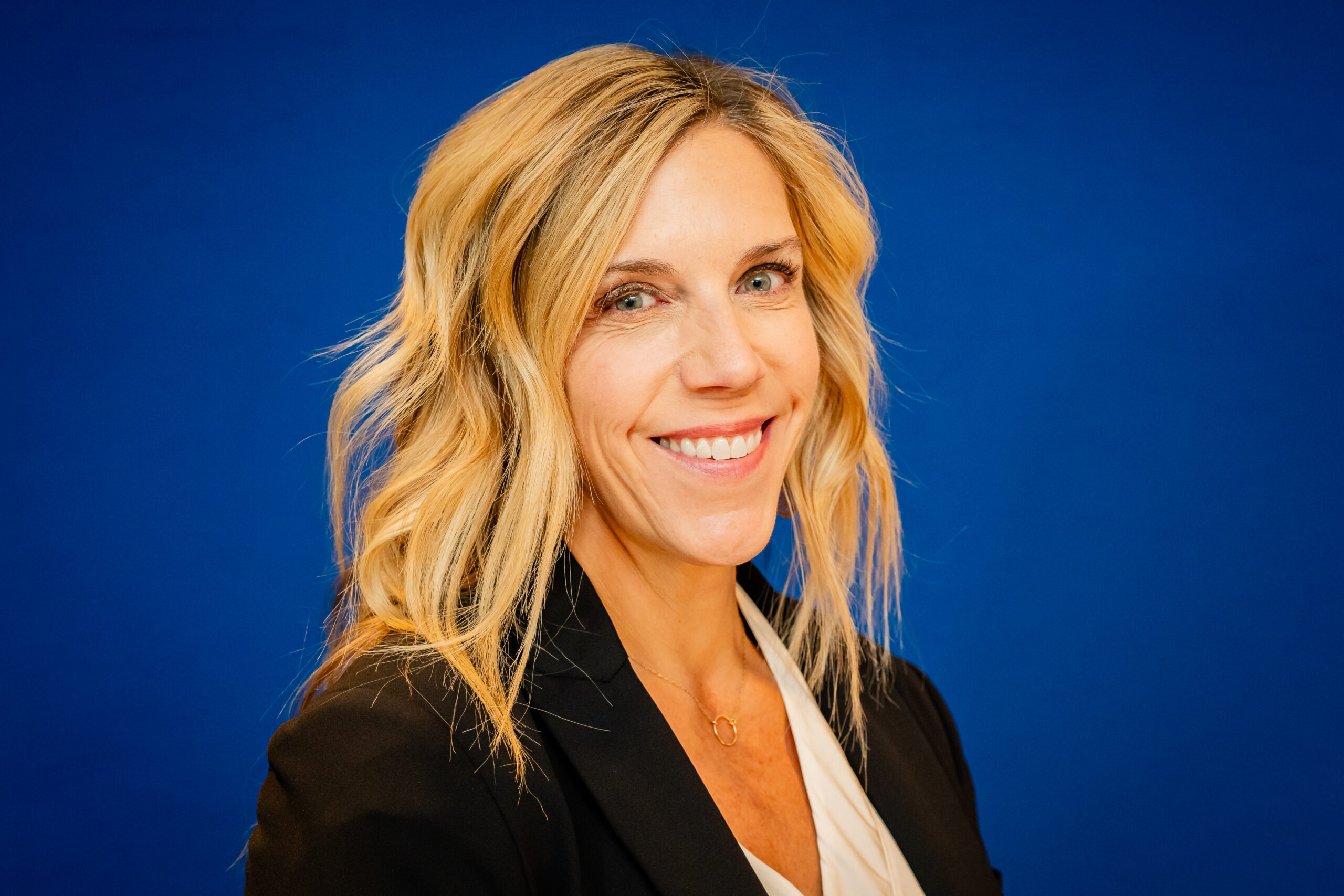 Smiling woman in business attire against blue background