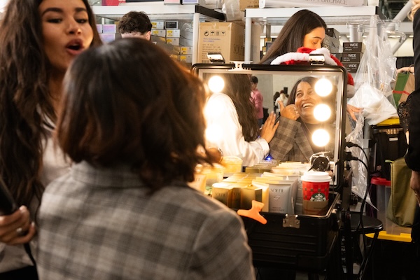 Woman getting makeup applied in dressing room