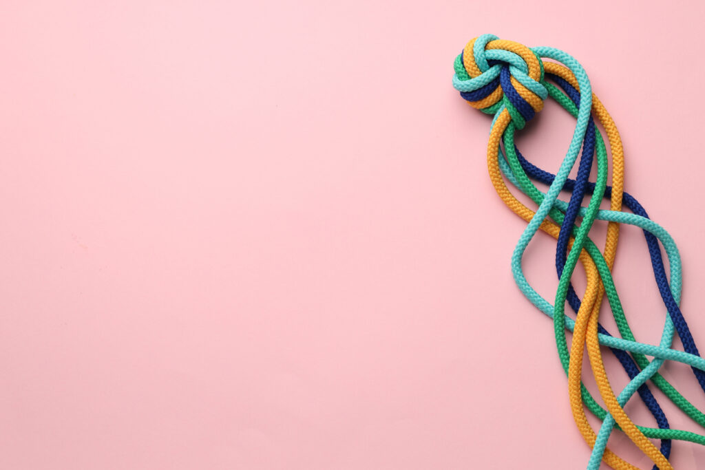 Colorful tangled ropes on pink background