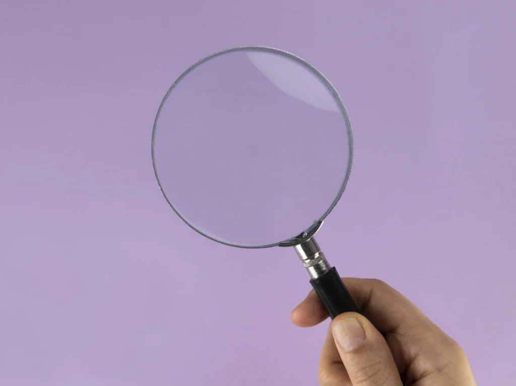 hand holding magnifying glass against purple background